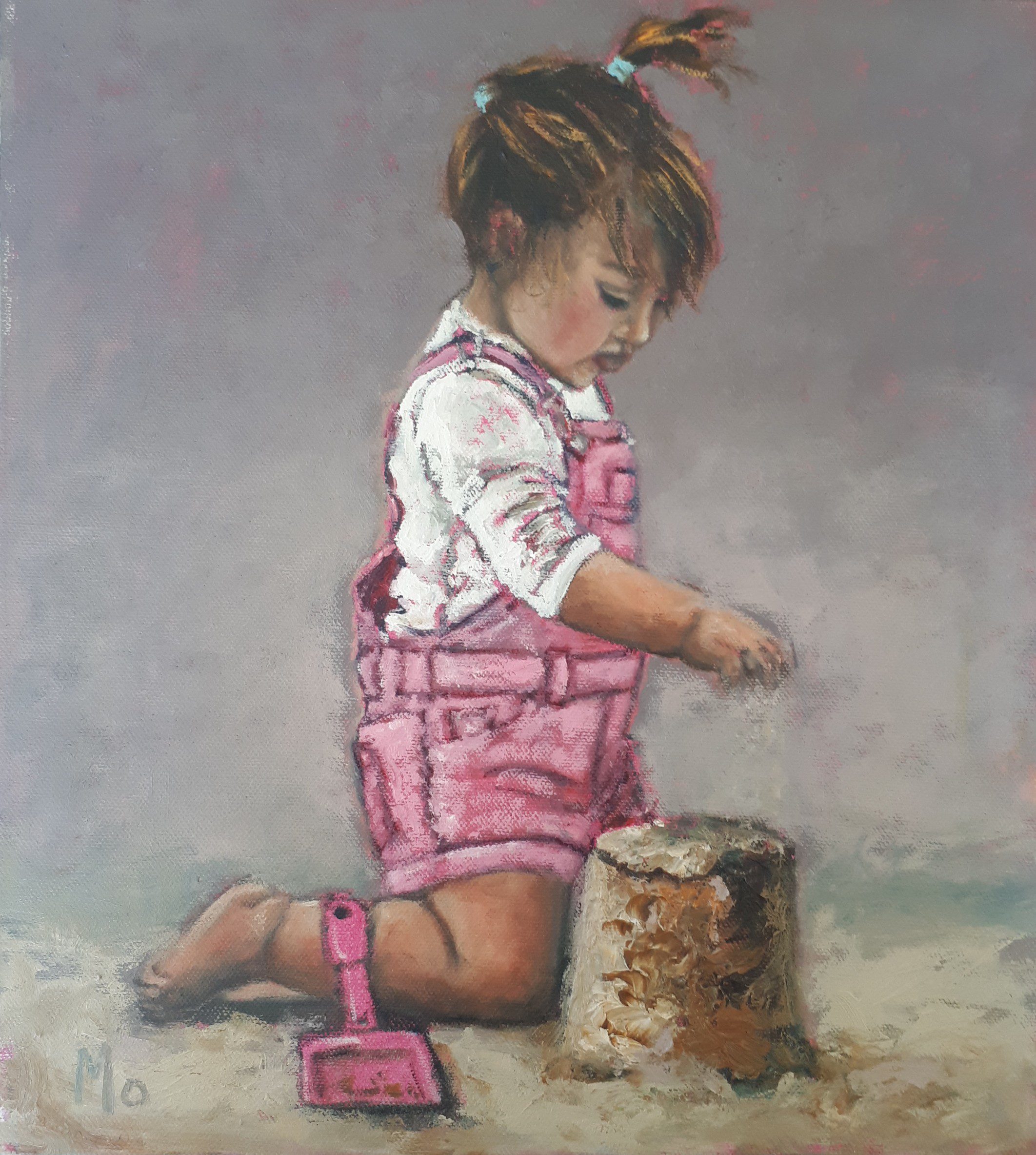 Little girl pink dungarees and pigtails making sandcastle