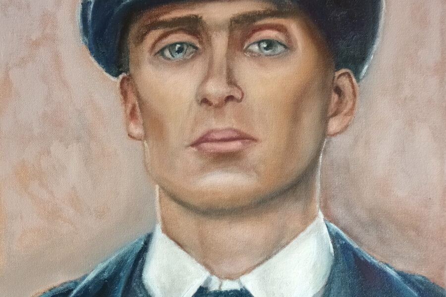 headshot of a man is a shirt and tie wearing an overcoat and a Peaky Blinder cap